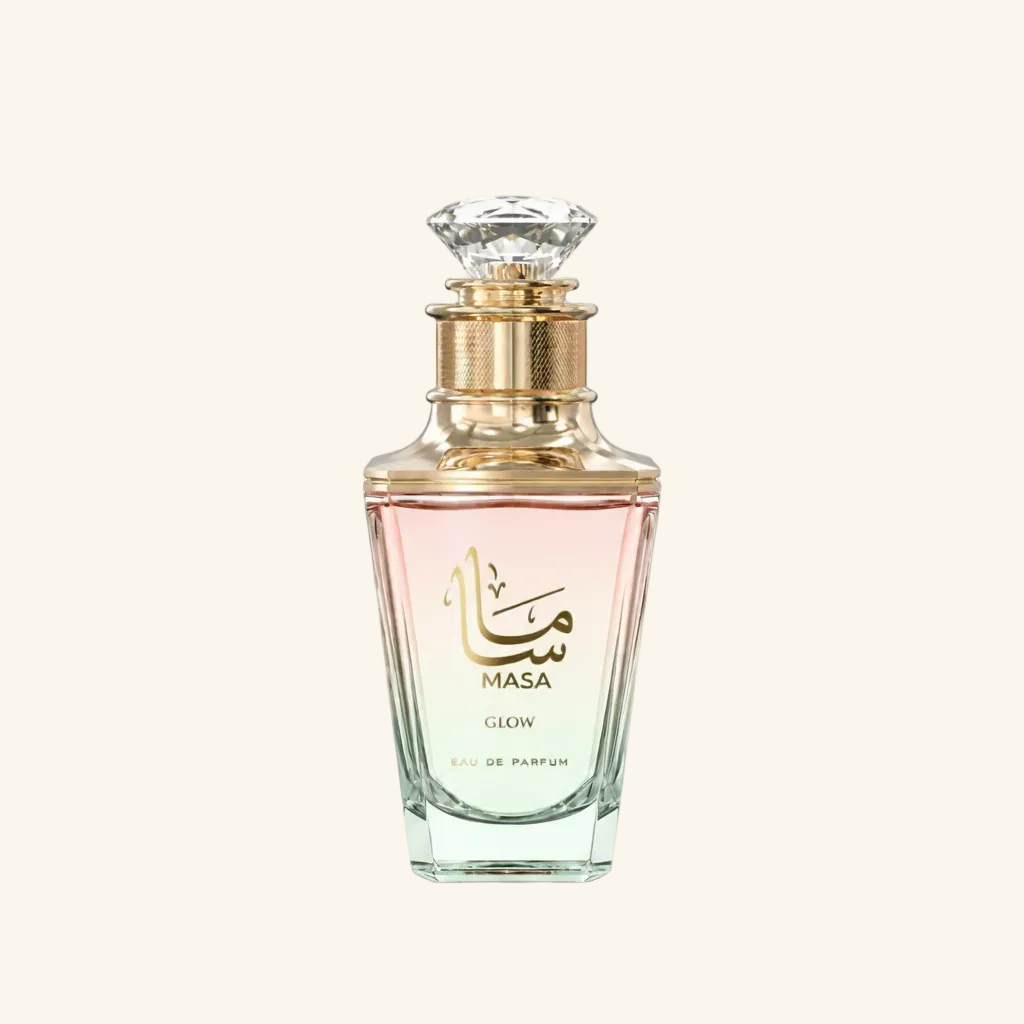 Masa Glow Eau de Parfum bottle with a faceted clear glass body, gold collar, and pink liquid inside, set against a solid off-white background.